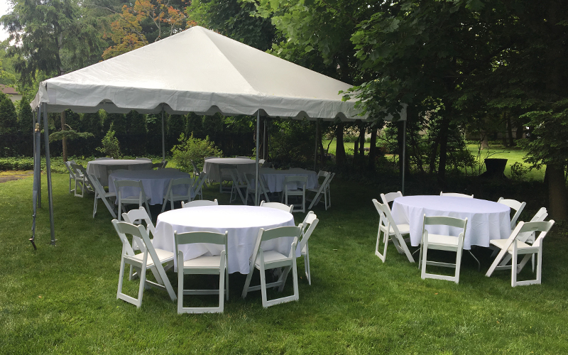 A beautifully decorated event tent set up in a backyard for a summer party.