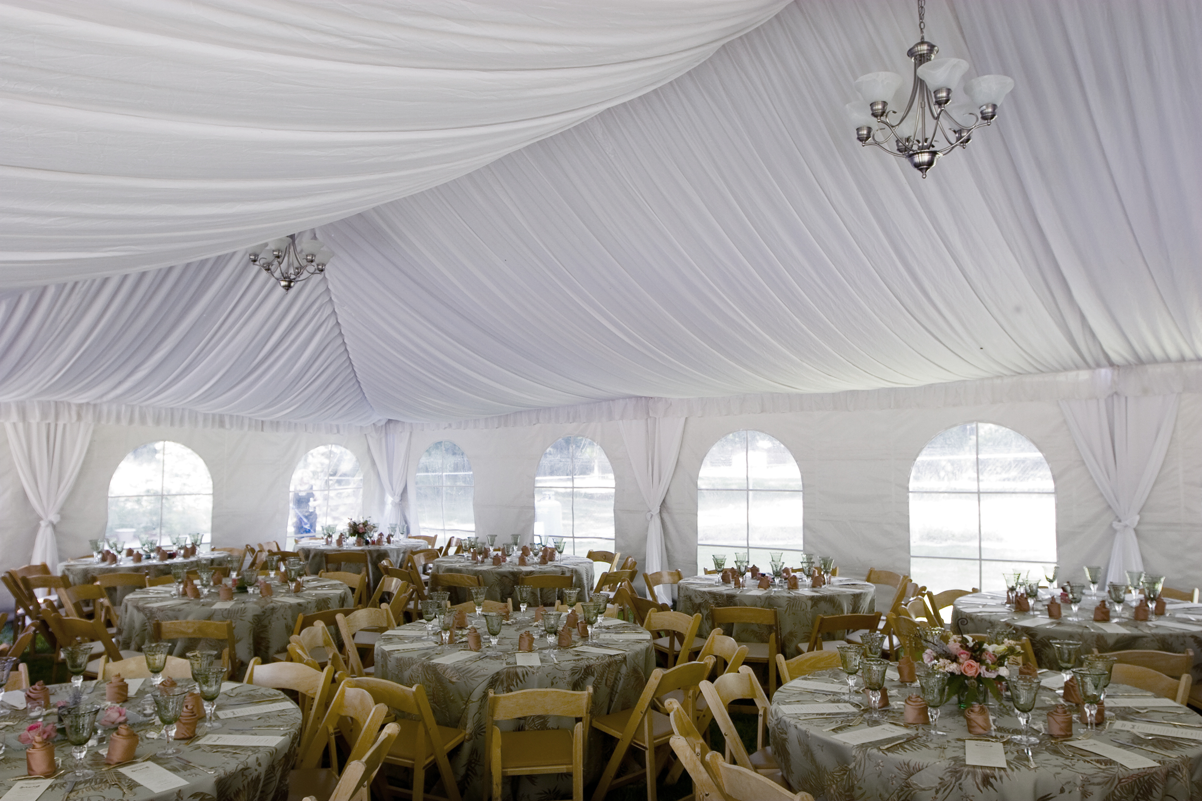 Tent liner interior of white frame tent wedding reception setup