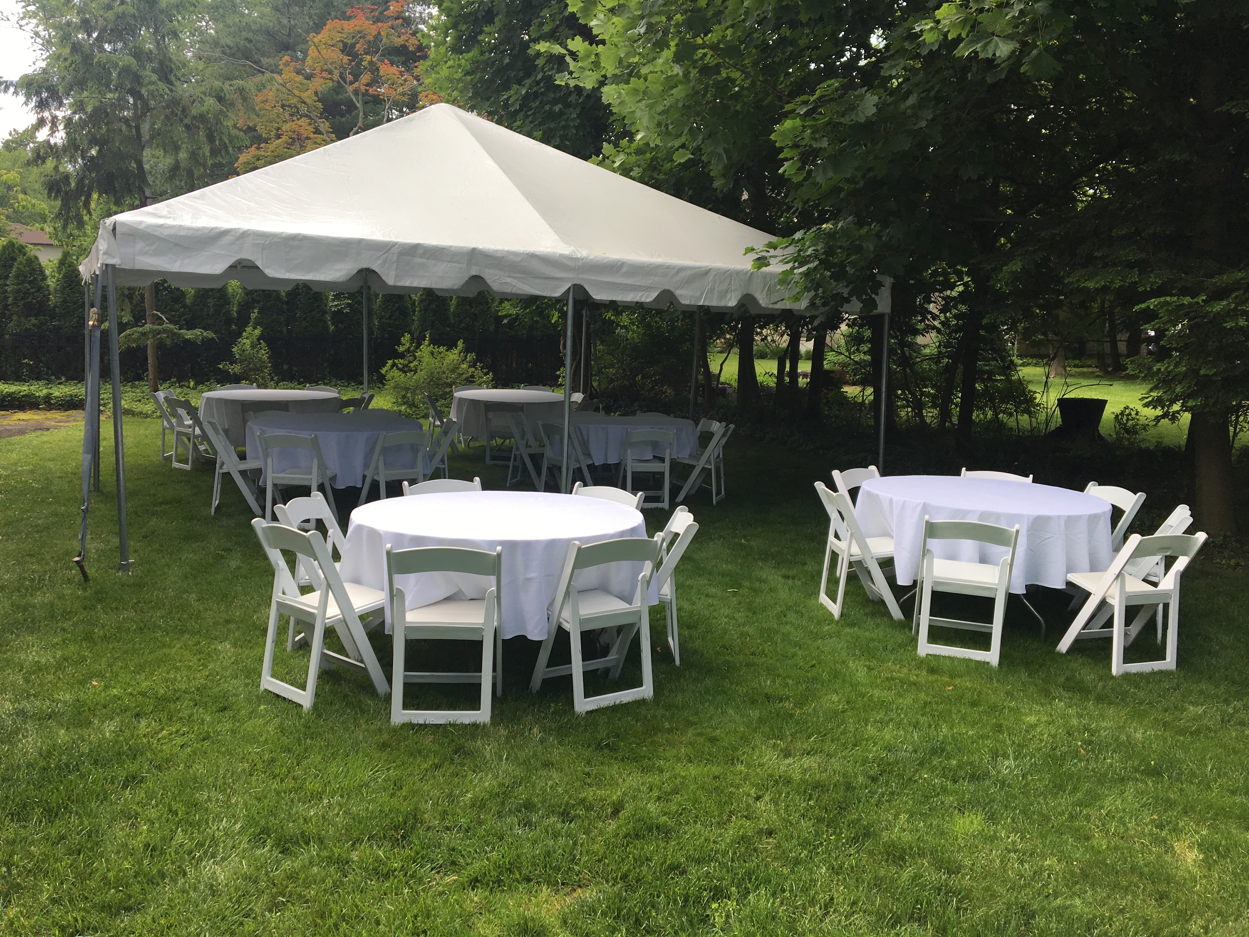 Small backyard tent party setup with tables and chairs