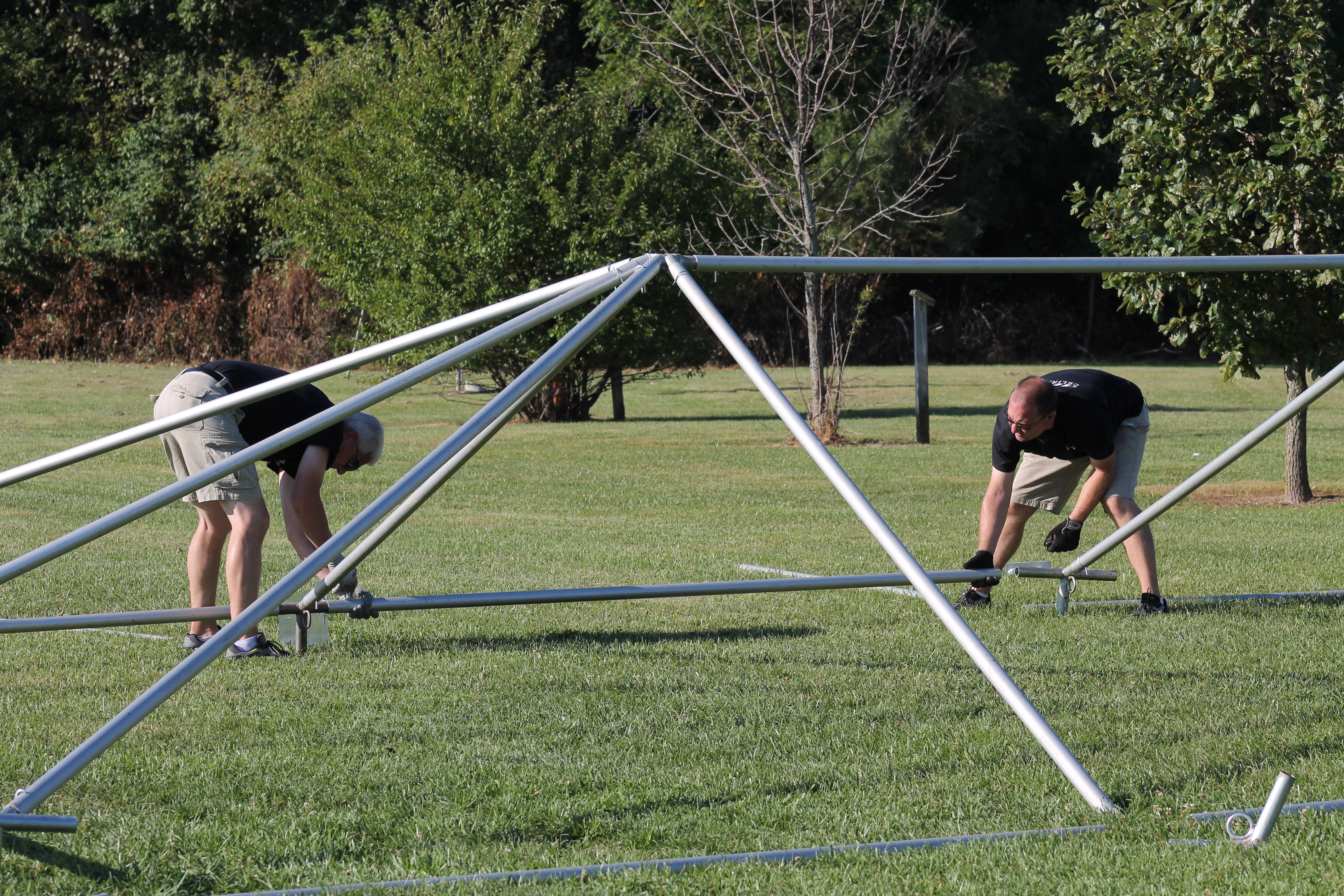Men installing frame tent tubing and fittings