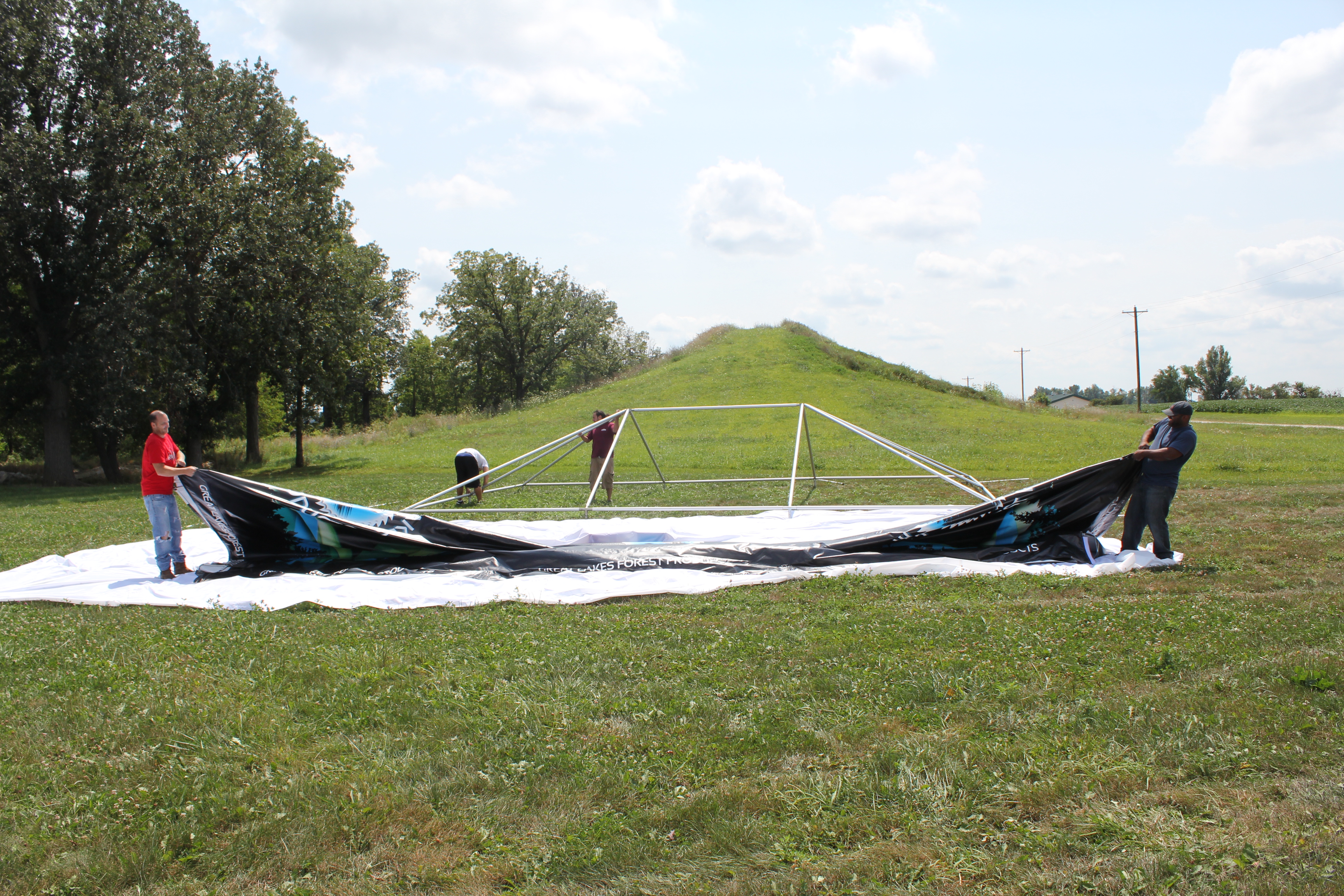 Installing a custom printed frame tent top using a drop cloth to protect the tent top
