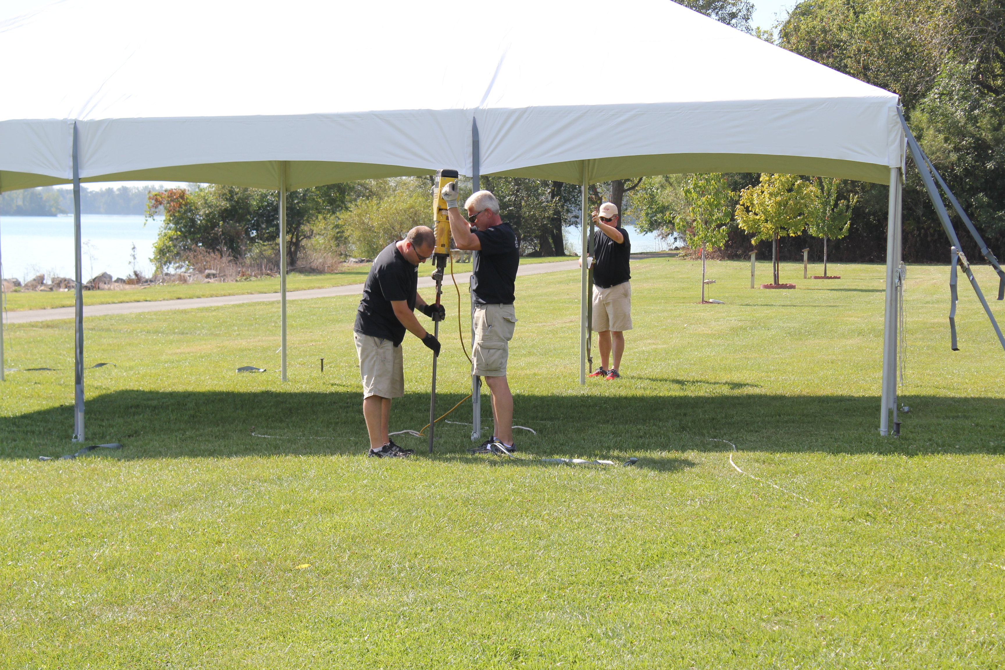 Men installing a tent and anchoring with stakes and a stake driver